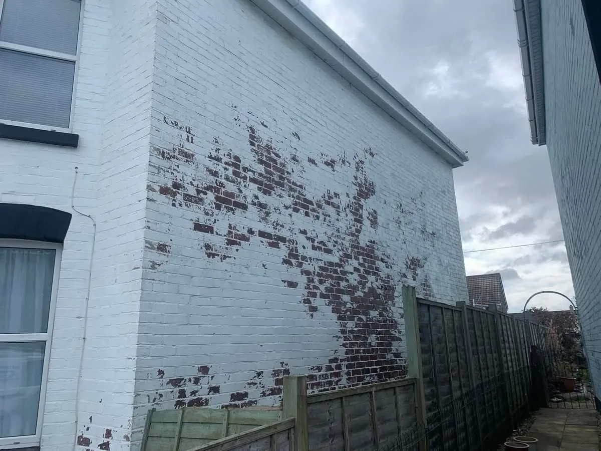 Peeling paint on a brick wall before redecoration in Helston